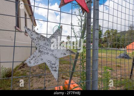 Wohlwollende Sterne auf temporärem Fechten, wo eines von vielen Geschäften in Cobargo, Australien, bei den Buschfeuern von 2019-20 zu Boden gebrannt wurde Stockfoto