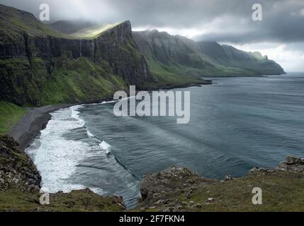 Blick über eine versteckte Bucht mit der Sonne, die durch die Wolken filtert, Färöer-Inseln, Dänemark, Europa Stockfoto