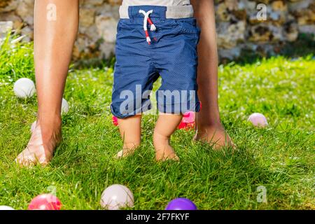 Kleinkind Junge lernen, auf dem Gras mit der Mutter zu gehen Stockfoto