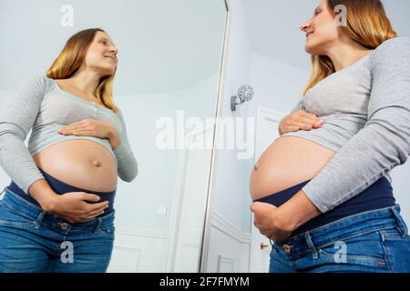 Späte Schwangerschaft Frau posiert Blick in den Spiegel Stockfoto