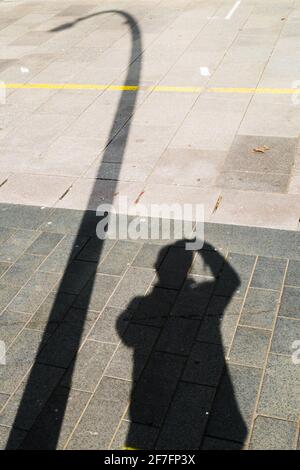 Schatten eines Fotografen und einer Lampost Stockfoto
