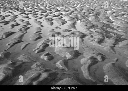 Wellen im Sand, die durch die zurücktretende Flut verursacht werden. Stockfoto