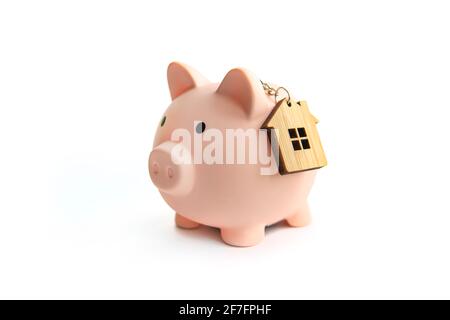 Sparschwein und Schlüsselhaus vor weißem Hintergrund isoliert. Das Konzept des Sparens für Ihre Immobilie. Sparen Sie bei der Miete. Stockfoto