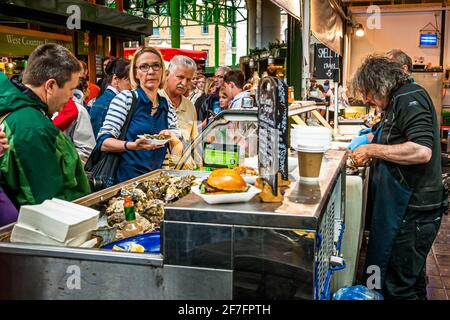 Der Borough Market in London ist am Wochenende recht turbulent. Man muss auch bei Austern Schlange stehen. Wer Burger de luxe oder Burritos mag, muss länger warten Stockfoto