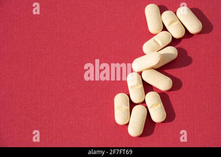 Vitamin-B-Pillen auf rotem Papierhintergrund mit Kopie Platz Stockfoto
