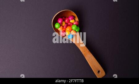 Mehrfarbiges Bonbon-Set mit einem Holzlöffel Stockfoto