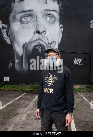 Der Straßenkünstler Akse steht vor seinem Wandbild von Joy Divisons Frontmann Ian Curtis. Stockfoto