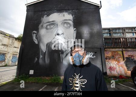 Der Straßenkünstler Akse steht vor seinem Wandbild von Joy Divisons Frontmann Ian Curtis. Stockfoto