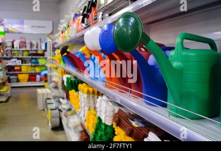 Nahaufnahme von mehrfarbigen Gießkannen aus Kunststoff in den Regalen in einem Geschäft mit Waren für die Gartenarbeit. Stockfoto