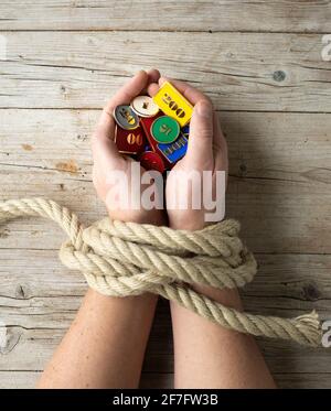 Die Hände des Menschen sind mit einem Seil gebunden und in seinen Händen hält er Token, Chips, Konzept sucht, Glücksspiel sucht Stockfoto