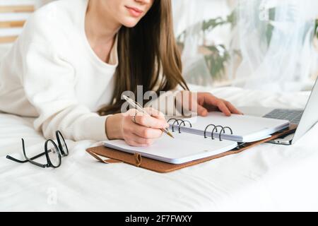 Frau schreibt im Notebook mit Laptop Stockfoto