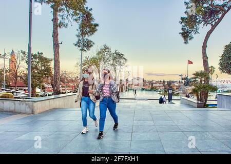 Die türkische Stadt Antalya, zwei Frauen mit schützenden Gesichtsmasken, eilen nach Hause, bevor die Ausgangssperre wegen einer COVID-19-Coronavirus-Infektion endet. Stockfoto