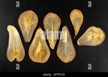Sieben Scheiben getrocknete Ananas auf schwarzem Hintergrund. Stockfoto