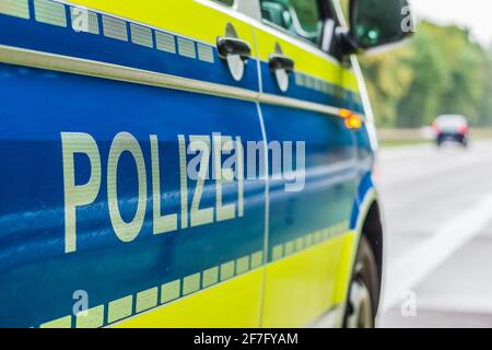 Seitenperspektive der Beifahrerseite des Polizeiwagens auf der Autobahn. Schriftzug Polizei auf dem Körper mit Boom und gelbem Hintergrund. Harte Schulter, Stockfoto