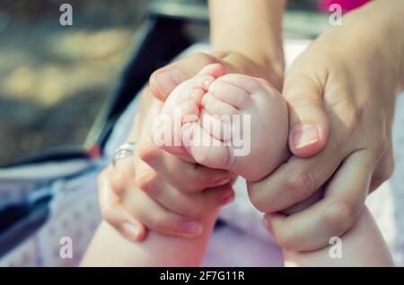 Babyfüße in den Händen der Mutter. Foto von Mutter und Baby.Sanftes Bild eines Kinderfußes Stockfoto