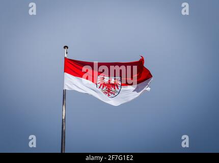 Potsdam, Deutschland. April 2021. Die Flagge des Landes Brandenburg fliegt auf dem Dach der Staatskanzlei gegen einen dunklen Himmel. Quelle: Soeren Stache/dpa-Zentralbild/ZB/dpa/Alamy Live News Stockfoto