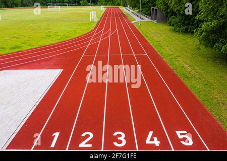 Perspektivische Ansicht eines Freiluftstadions mit rot nummerierten Laufstrecken, Infrastruktur für sportliche Aktivitäten Stockfoto