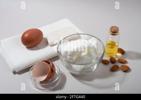 Inhaltsstoffe der Maske „Eierweiß“. Geschlagenes Eiweiß und Mandelöl. Stockfoto