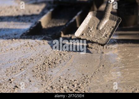 Gießen von Betonplatten. Nivellierung einer Betonplatte mit einem Handwerkzeug. Schaufelschaufel hilft, mit Zement zu arbeiten. Stockfoto