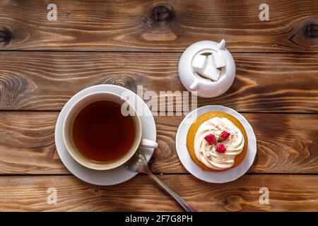 Biskuitkuchen mit Sahne, verziert mit kleinen Blumen und einer Tasse Tee. Das Konzept eines festlichen Leckerbissen. Handarbeit Stockfoto