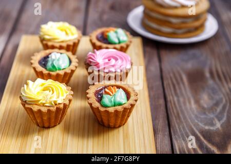 Shortbread und Biskuit und Cremekuchen mit kleinen Blumen und einer Tasse Tee dekoriert. Das Konzept eines festlichen Leckerbissen. Handarbeit Stockfoto