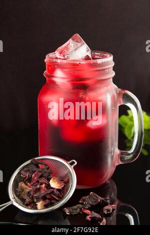 Hibiskus- oder Karkadentee im Glas auf schwarzem Hintergrund. Position vertikal. Nahaufnahme. Stockfoto