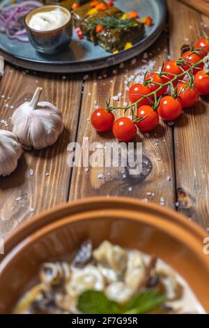 Knoblauch, Kirschtomaten, Chilischoten und andere Gerichte auf braunem Holzhintergrund. Stockfoto