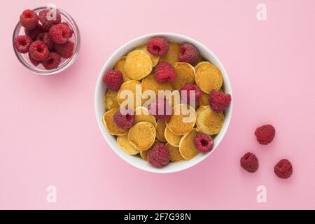 Draufsicht auf Mini-Pfannkuchen mit Himbeeren in Weiß Schüssel auf dem rosa Hintergrund Stockfoto