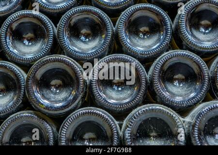 Die Enden der Weinflaschen, die im Weinkeller mit Staub bedeckt sind. Die Textur des Glases. Stockfoto