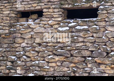 Ein Fragment einer Mauer mit Mauerwerk und kleinen schmalen Fenstern. Die Textur des Steins. Stockfoto