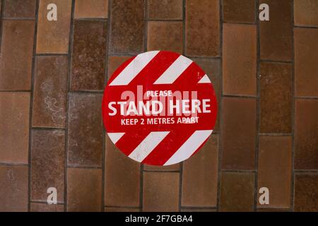 London, Ontario, Kanada - 6 2021. Februar: Ein Bodenschild in der Nähe der Bibliothek der Sherwood Forest Mall fordert die Besucher auf, sechs Meter von anderen in der Schlange zu stehen. Stockfoto