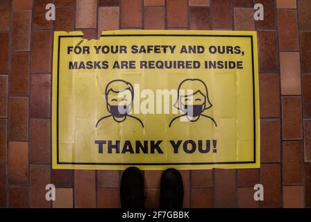 London, Ontario, Kanada - 6 2021. Februar: Ein gelber Bodenaufkleber in der Sherwood Forest Mall fordert Käufer auf, Masken zu tragen, während sie drinnen einkaufen. Stockfoto