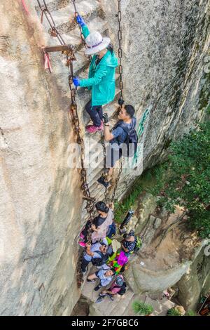 HUA SHAN, CHINA - 4. AUGUST 2018: Menschen klettern steile Treppen, die zu den Gipfeln des Hua Shan Berges in der Provinz Shaanxi, China, führen Stockfoto