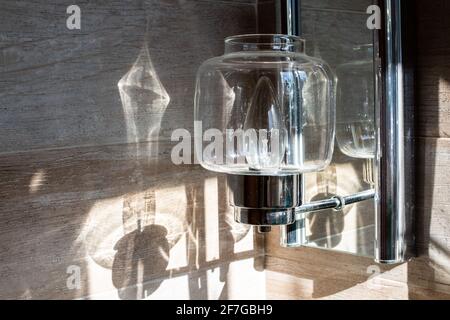 Foto einer durchsichtigen Glasleuchte, die Sonnenlicht an der Wand in einem Badezimmer in London, Ontario, Kanada reflektiert. Stockfoto