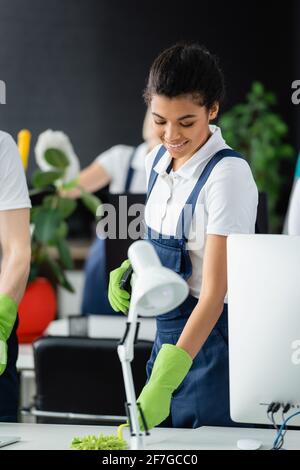 afroamerikanische Putzfrau und lächelnd im Büro Stockfoto