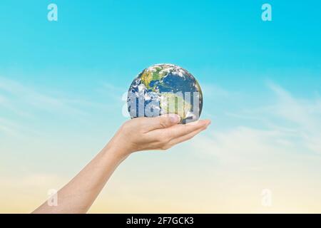Globus in Händen über blauem Himmel Hintergrund. Rette die Erde. Elemente dieses Bildes, die von der NASA eingerichtet wurden Stockfoto