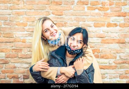 Junge Menschen sitzen auf einer Bank Stadtstraße gegen ein Ziegelwand als Hintergrund trägt Gesicht schützende masks.Coronavirus Prävention, Reisen Sicher Stockfoto