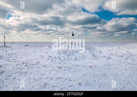 Grand Bend, Ontario, Kanada - EIN Mann geht vom Rand des Grand Bend Pier zurück, wo der Leuchtturm auf einen dicken Eisteppich blickt. Stockfoto