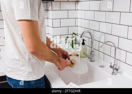 Ein Mann wäscht Geschirr in der Küche mit einem Holz Eco-Bürste Stockfoto