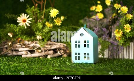 Blaues Haus aus Pappe auf dem Hintergrund des grünen Frühlingsgrases. Dorfhaus Konzept Stockfoto