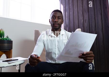 Porträt eines afroamerikanischen Geschäftsmannes, der ein Dokument hält Sessel Stockfoto