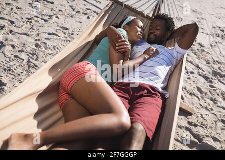 Glückliches afroamerikanisches Paar, das in einer Hängematte am Strand liegt Umarmen Stockfoto