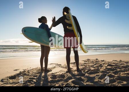 Glückliches afroamerikanisches Paar am Strand mit hohen Surfbrettern Fünf Stockfoto