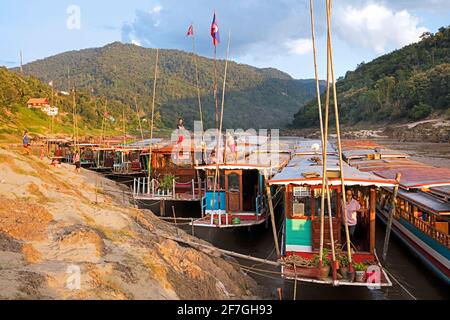 Slowboats / Slow Boats für Flusskreuzfahrten nach Luang Phabang / Luang Prabang / Louangphabang auf dem Mekong bei Sonnenuntergang, Laos Stockfoto