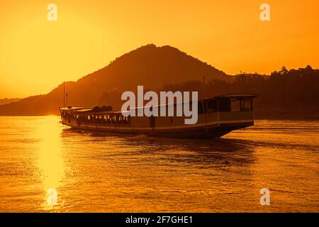 Traditionelles Slowboat / Slowboat für Flusskreuzfahrt nach Luang Phabang / Luang Prabang / Louangphabang auf dem Mekong River bei Sonnenuntergang, Laos Stockfoto