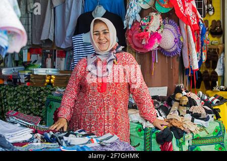 Kirgisische Frau mit goldenen Zähnen verkauft Kleidung auf dem Markt in der Stadt Osch, Kirgisistan Stockfoto