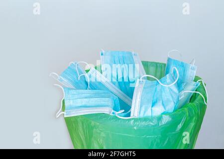 Benutzte infektiöse Maske, die in den Abfalleimer geworfen wurde. Weggeworfene Einweg-OP-Masken. Konzept für medizinische Abfälle Stockfoto