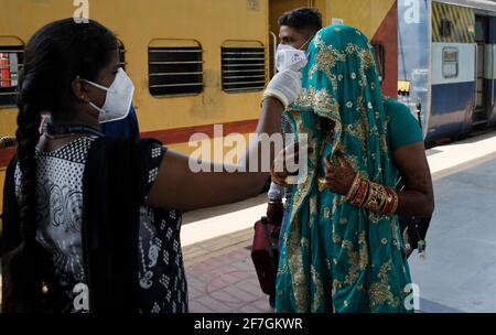 Ein Mitarbeiter des Gesundheitswesens überprüft die Temperatur einer Frau bei der Ankunft mit dem Zug in Dadar Terminus. Passagiere, die in Zügen aus dem Bundesstaat Gujarat nach Mumbai ankommen, werden auf Sauerstoffgehalt überprüft. Die Temperatur und falls Fieber festgestellt wird, müssen sie sich am Bahnhof einem Abstrichtest unterziehen, bevor sie zu ihrem jeweiligen Ziel fahren dürfen. Stockfoto