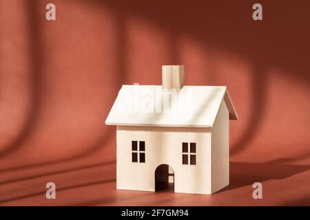 Holzhaus Gebäude Miniaturmodell mit Schatten auf braunem Hintergrund. Home, Sweet Home. Kauf neuer Wohnung, Hypothek, Miete, Geschäftsimmobilien Stockfoto