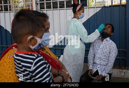 Mumbai, Indien. April 2021. Ein Mitarbeiter des Gesundheitswesens, der einen Anzug für persönliche Schutzausrüstung (PSA) trägt, holt bei der Ankunft am Dadar Terminus einen Nasenabstrich von einem Mann ab.Passagiere, die in Zügen aus dem Bundesstaat Gujarat nach Mumbai kommen, werden auf Sauerstoffgehalt untersucht. Die Temperatur und falls Fieber festgestellt wird, müssen sie sich am Bahnhof einem Abstrichtest unterziehen, bevor sie zu ihrem jeweiligen Ziel fahren dürfen. (Foto von Ashish Vaishnav/SOPA Images/Sipa USA) Quelle: SIPA USA/Alamy Live News Stockfoto